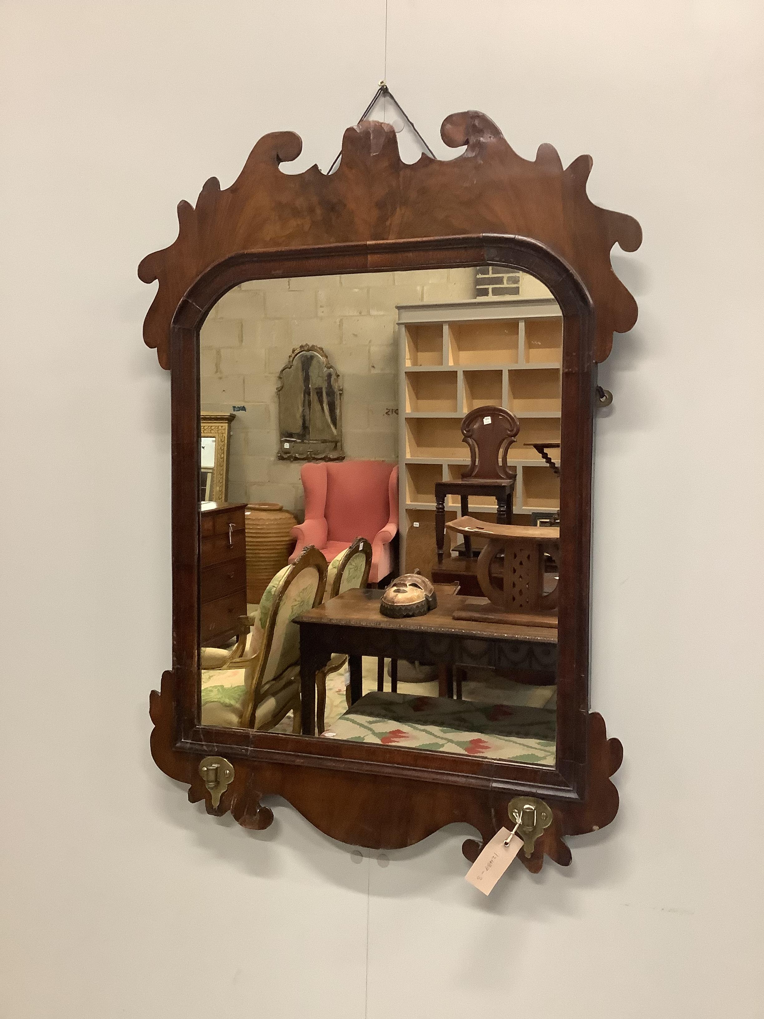 A George II walnut fret cut wall mirror, with candle arm brackets, width 58cm, height 84cm